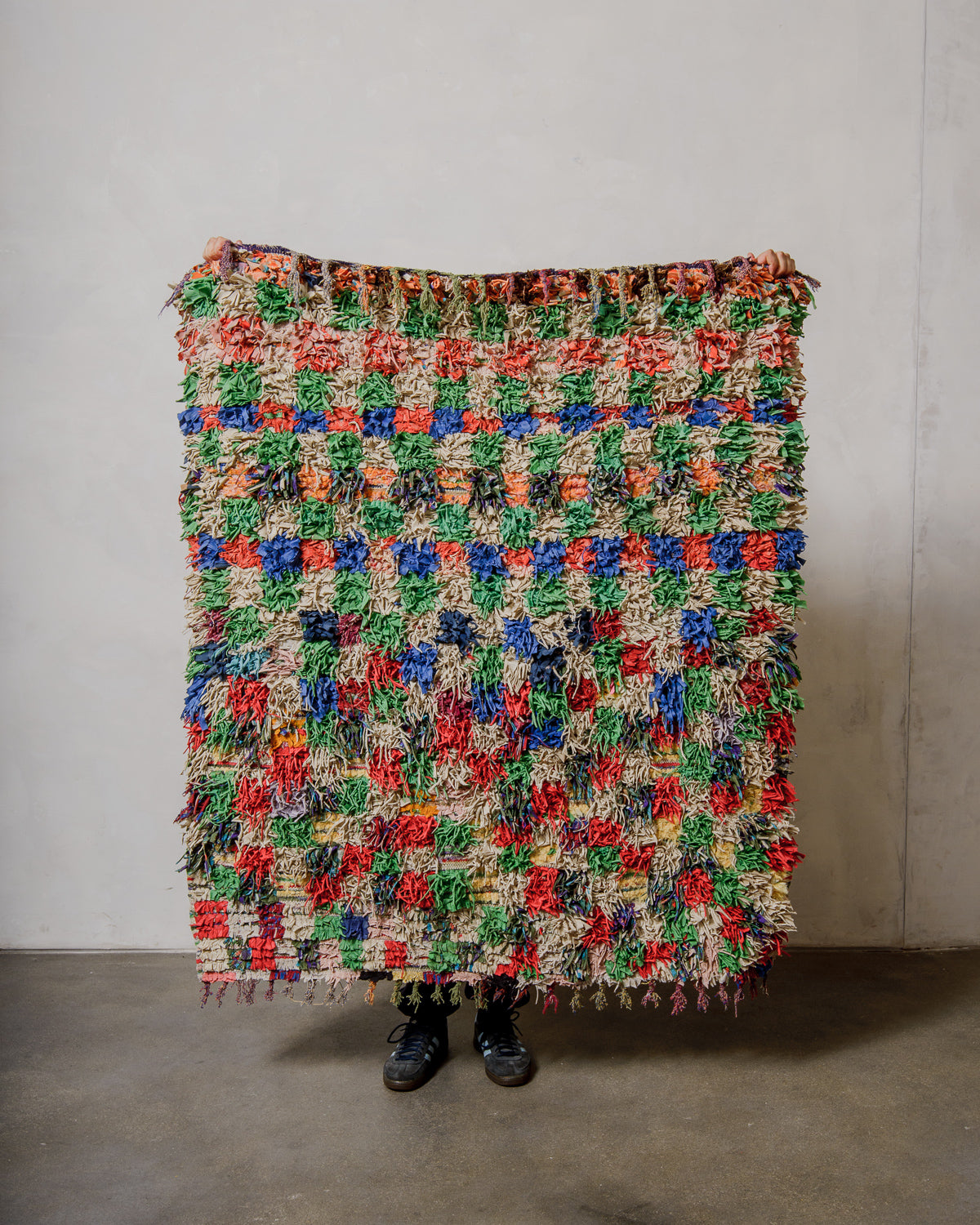Multicoloured textured rug against a plain wall.